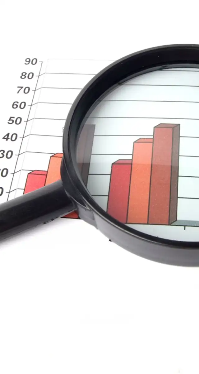 Et forstørrelsesglas, der ligger ovenpå nogle grafer i rød